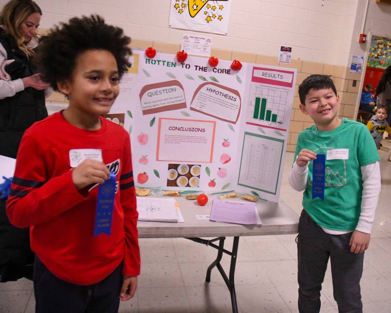 Students Sebastien Robinson, left, and Reece Framarin pose on Saturday Jan. 25, 2025, with their first prize ribbons Infront of their science project where they tested different liquids to prevent apples from browning during the Downers Grove District 58 science fair held at O’Neill Middle School.