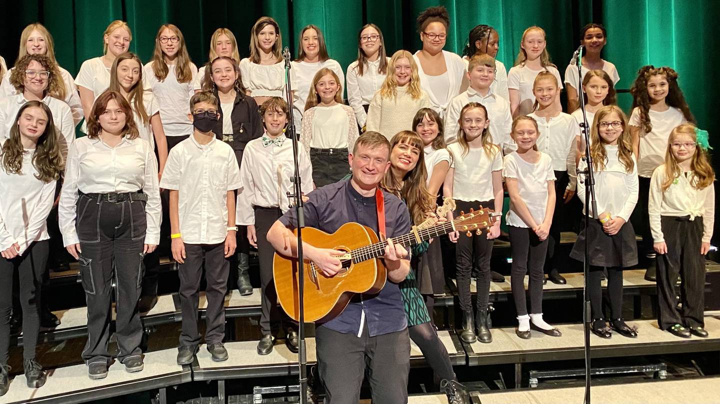 Aoife Scott and Andrew Meaney pose for a photo with choir students from two schools at District 202 in Plainfield, Drauden Point Middle School and Wesmere Elementary School, during their performances at the Rialto Square Theatre in Joliet on March 16, 2023.