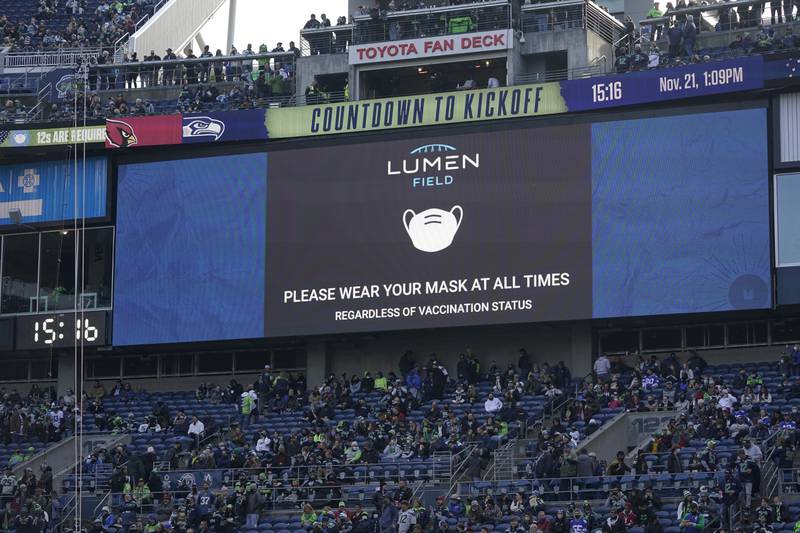 A video monitor reminds fans to wear a mask at all times because of the coronavirus pandemic before an NFL game between the Seattle Seahawks and the Arizona Cardinals, Sunday, Nov. 21, 2021, in Seattle.