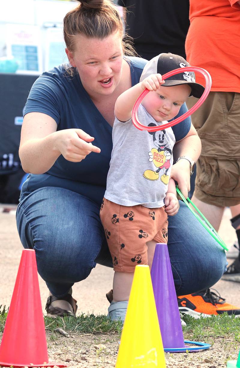 Brixton Kittleson, 1, from DeKalb, gets some help from his mom Kelli playing ringtoss at the DeKalb Park District booth Thursday, July 21, 2022, during the DeKalb Chamber of Commerce Family Fun Fest at Hopkins Park in DeKalb.