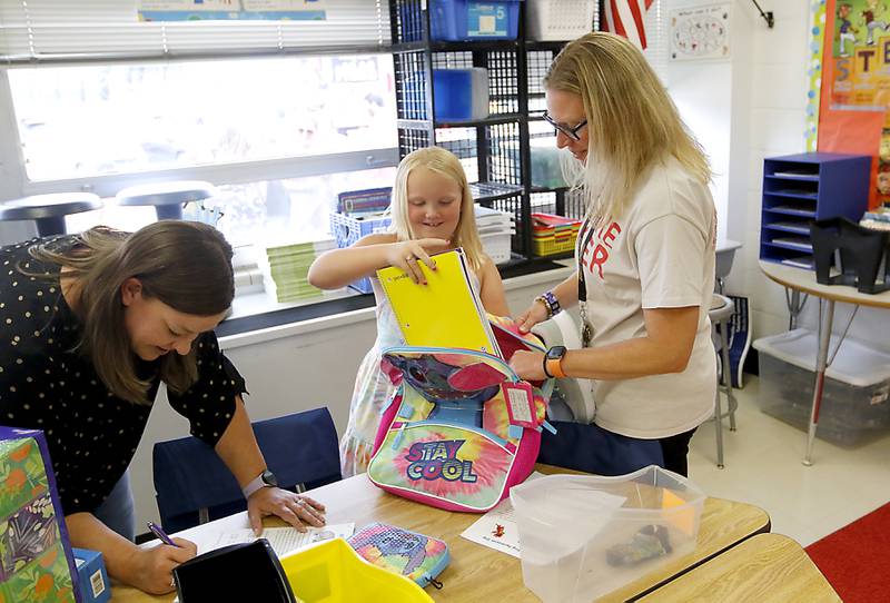 Olivia Nelson, 9, a fourth grader at Duker Elementary School in McHenry, unpacks her school supplies with the help of her teacher, Lisa Nellessen, on Tuesday, Aug. 15, 2023, as her mother, Sarah, filled out permission forms while dropping dropping off her school supplies.