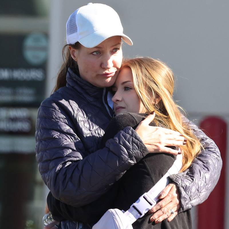 Two women hug among a group of Brian Bemis Toyota employees Wednesday, Oct. 23, 2024, outside the dealership in DeKalb after police responded to a stabbing where multiple employees were injured. The incident ended after police shot the man wielding the knife authorities said.