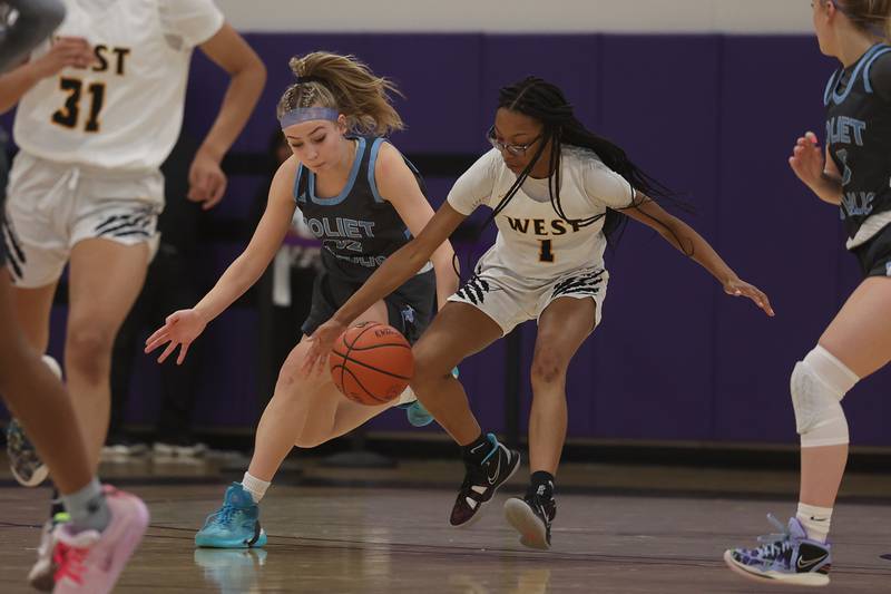 Joliet Catholic’s Emma Beattie and Joliet West’s Ashlei Thomas battle for the loose ball in the WJOL Basketball Tournament at Joliet Junior College Event Center on Monday