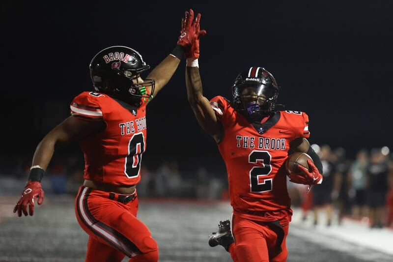 Bolingbrook’s Joshua Robinson (0) high fives Kyan Berry-Johnson (2) as he scores on a breakaway run against Minooka. Friday, Aug. 26, 2022, in Bolingbrook.