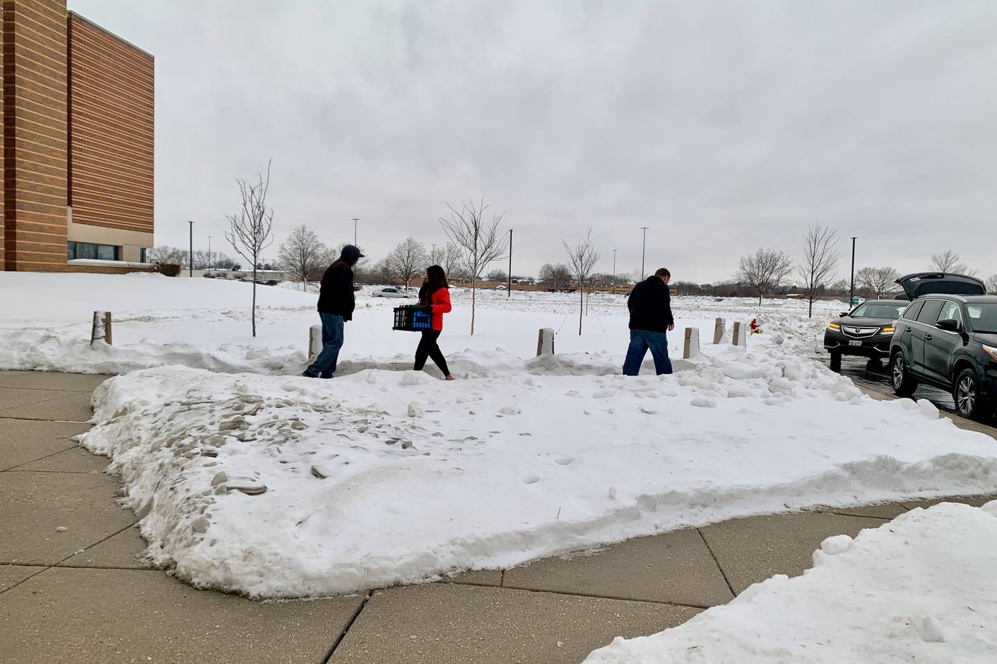 Grayslake Middle School teachers move supplies into the University Center of Lake County in the snow after a pipe burst at school's building in January 2024.