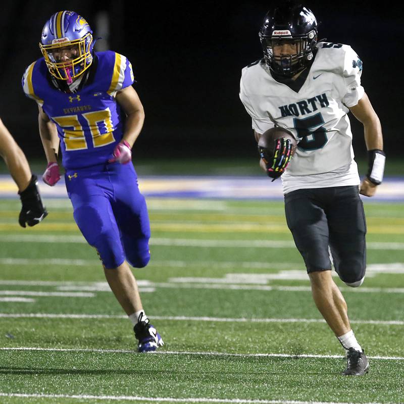 Woodstock North's Adan Castaneda returns the kickas he is chased by Johnsburg's Aiden Fouke during a Kishwaukee River Conference football game against Johnsburg on Friday, Sept. 26, 2025, at Johnsburg High School.
