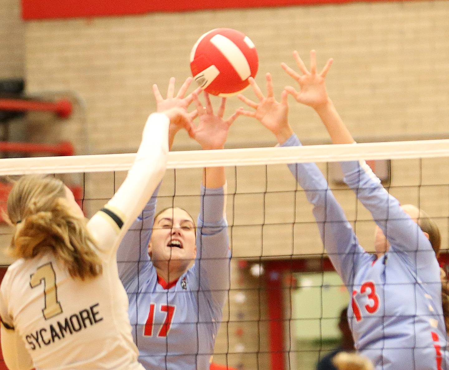 Sycamore's Laci Neece spikes the ball as Ottawa's Olivia Evola and teammate Ayla Dorsey block it on Thursday, Oct. 12, 2023 at Kingman Gym.