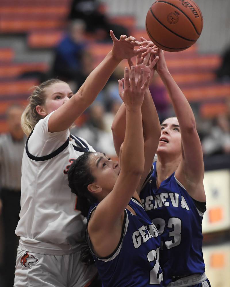 Naperville North’s Kendall Johnson and Geneva’s Leah Palmer and Lucie Garnier, right, reach for the ball in a girls basketball game in Naperville on Tuesday, Nov. 28, 2023.