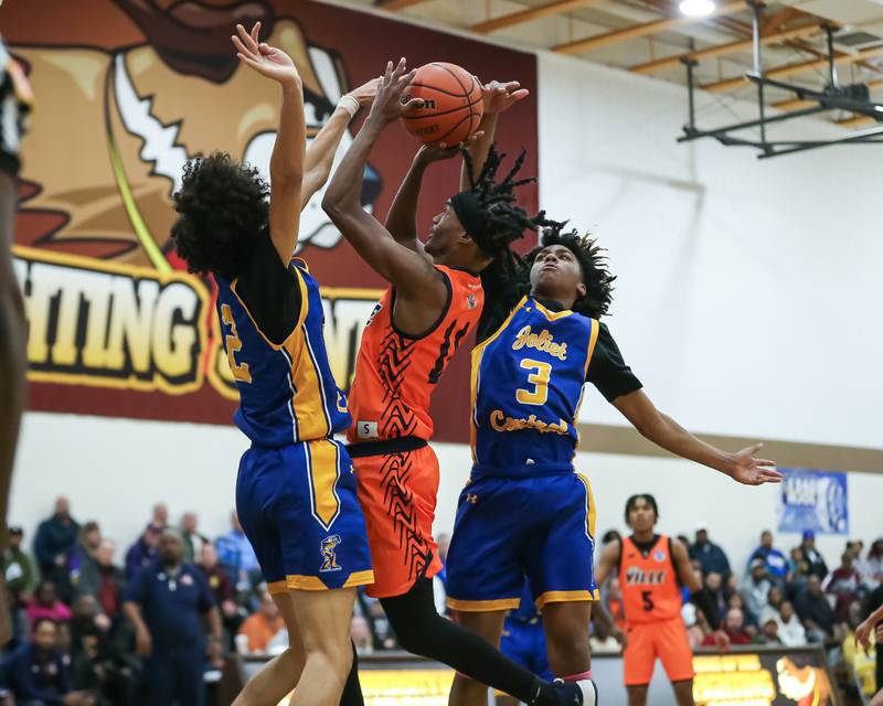 Romeoville's TJ Lee (11) is challenged by Joliet Central's Glenn Harper (3) and Zion Kostyra (2) at the basket  in the WJOL Tournament Championship game. Nov 25, 2023.