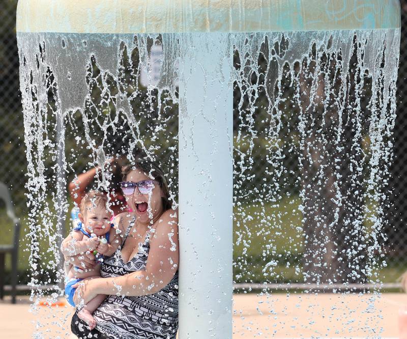 Serenity Stensrud, and her daughter Layla Pennington, 1, from DeKalb, stand under one of the water features Tuesday, July 25, 2023, at Hopkins Pool in DeKalb.