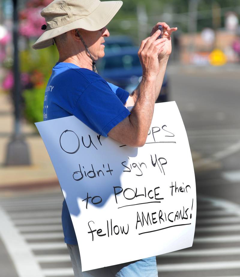 A participant in the "Workers Over Billionaires" rally in downtown Oregon takes a photo as he stands with his sign in downtown Oregon on Monday, Sept. 1, 2025. The event also included pro-Trump signs.