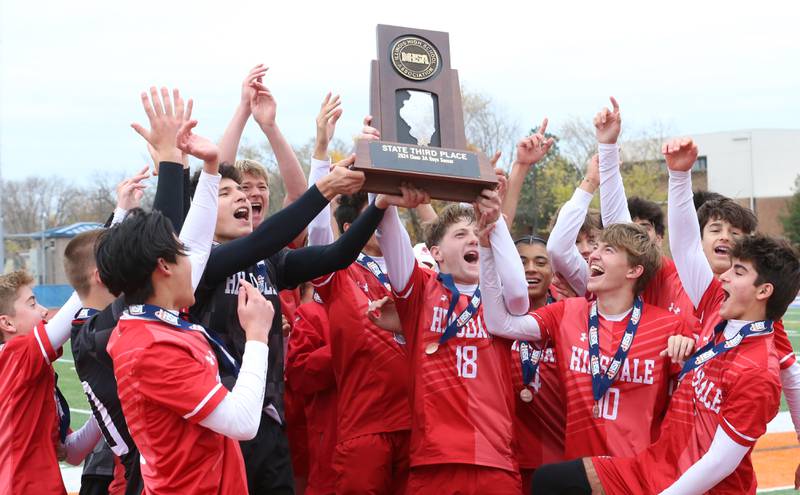 Members of the Hinsdale soccer team hoist the Class 1A State third-place trophy after defeating Edwardsville 3-1 on Saturday, Nov. 9, 2024 at Hoffman Estates High School.