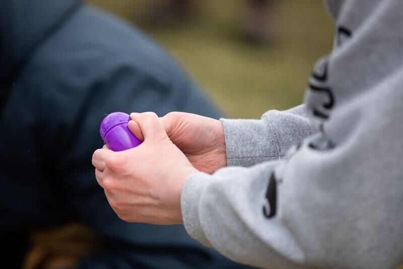 An Easter egg hunter opens an Easter egg during the Elmhurst Park District's Adult Easter Egg Hunt at Wilder Park on Saturday, March 18, 2023.