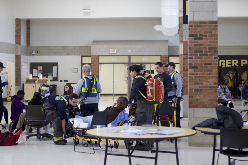 Paramedics providing treatment to student actors inside Joliet West High School on Tuesday, March 25, 2025, as part of a staged emergency drill simulating the aftermath of a gas explosion.