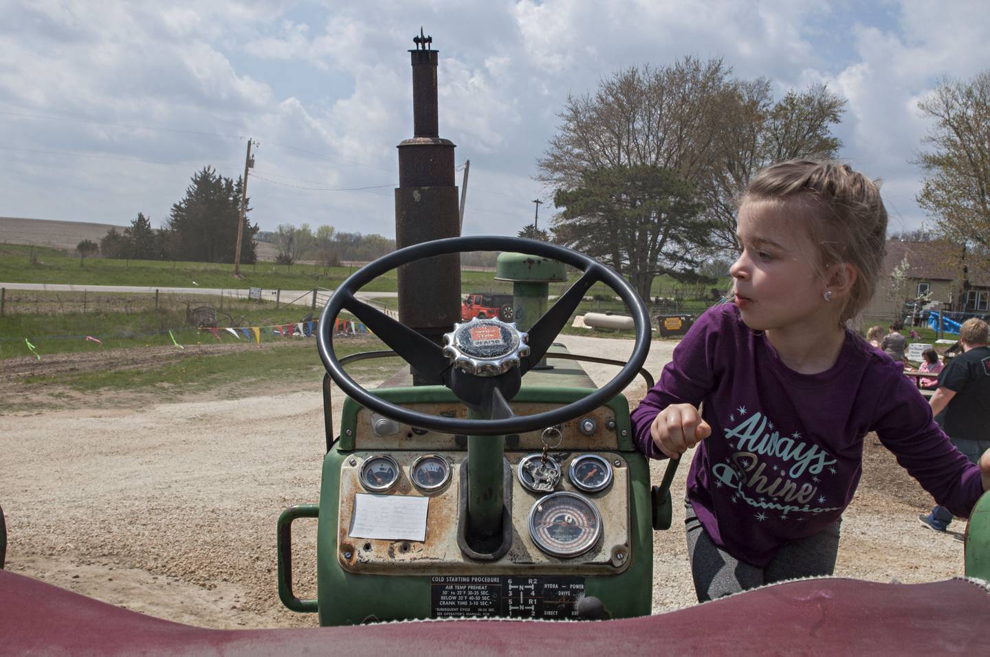 Annalee King, 5, of Thomson climbs to the seat of a tractor Saturday while visiting the farm. Along with the animals, the farm had some equipment on display, crafts for sale and food.