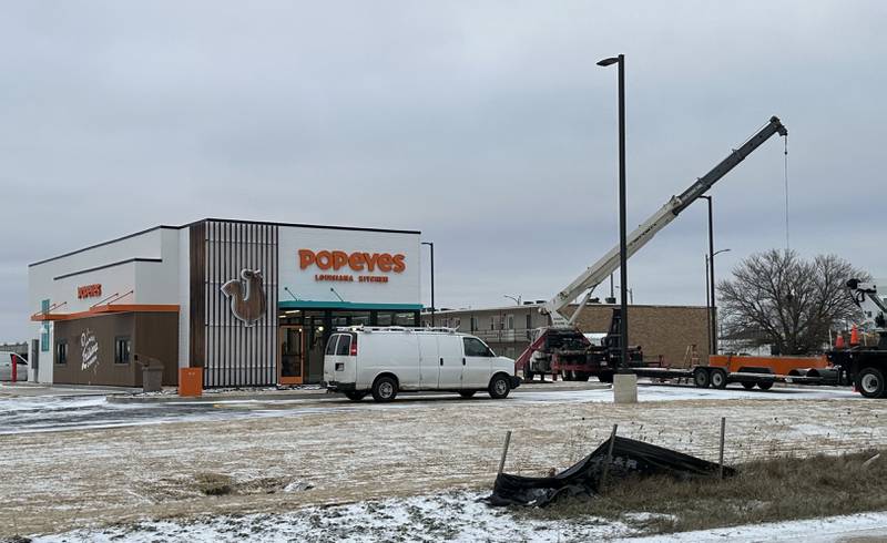 Crews hoist Popeyes signs in place for the new location near the intersection of May Road and Trompeter Road on Tuesday, Dec. 3, 2024 in Peru.
