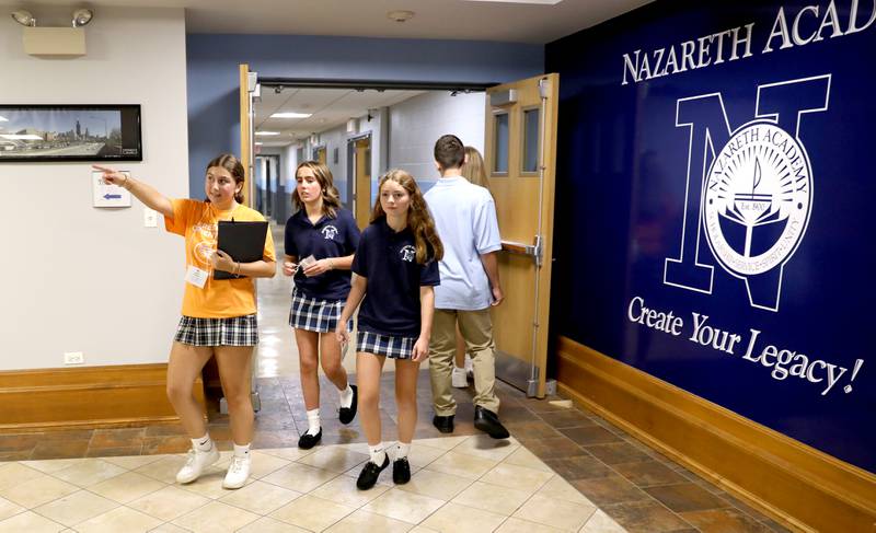 Nazareth Academy student leader Sofia Klinger (far left) leads freshmen Lizzie Nelson (center) and Lucy Gergits (right) through the halls of the La Grange Park school during freshman orientation on Thursday, Aug. 17, 2023.