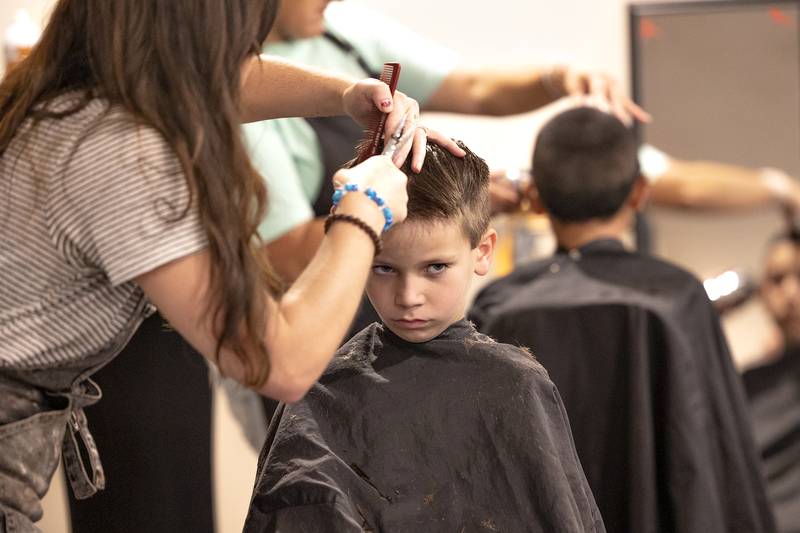Perhaps not looking forward to missing out on the lazy days of summer, Kegan Zacharias 8, gets a trim for the first day of school Thursday, August 7, 2025, at Dixon’s Tools for School.