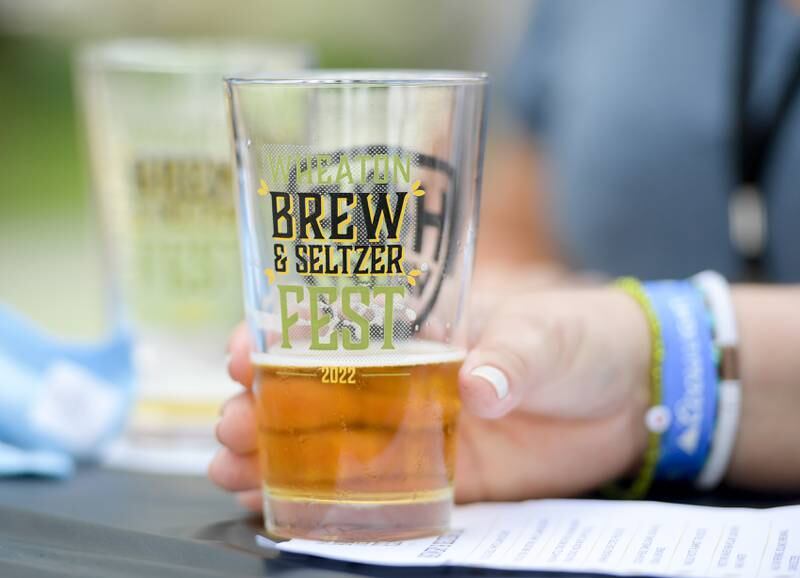 A patron holds her 2022 Wheaton Brew and Seltzer Fest pint glass during fest in Memorial Park on Saturday, August 6, 2022.