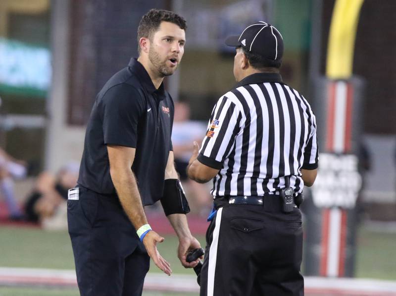 DeKalb head coach Derek Schneeman talks to an official about a call during the First National Challenge game Friday, Aug. 25, 2023, in Huskie Stadium at Northern Illinois University in DeKalb.
