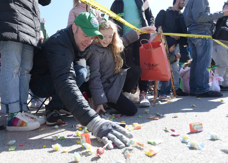 Mark Chmura and his daughter Ella of Elmhurst sweep up candy while attending the Elmhurst St. Patrick's Day Parade Saturday, March 9, 2024.