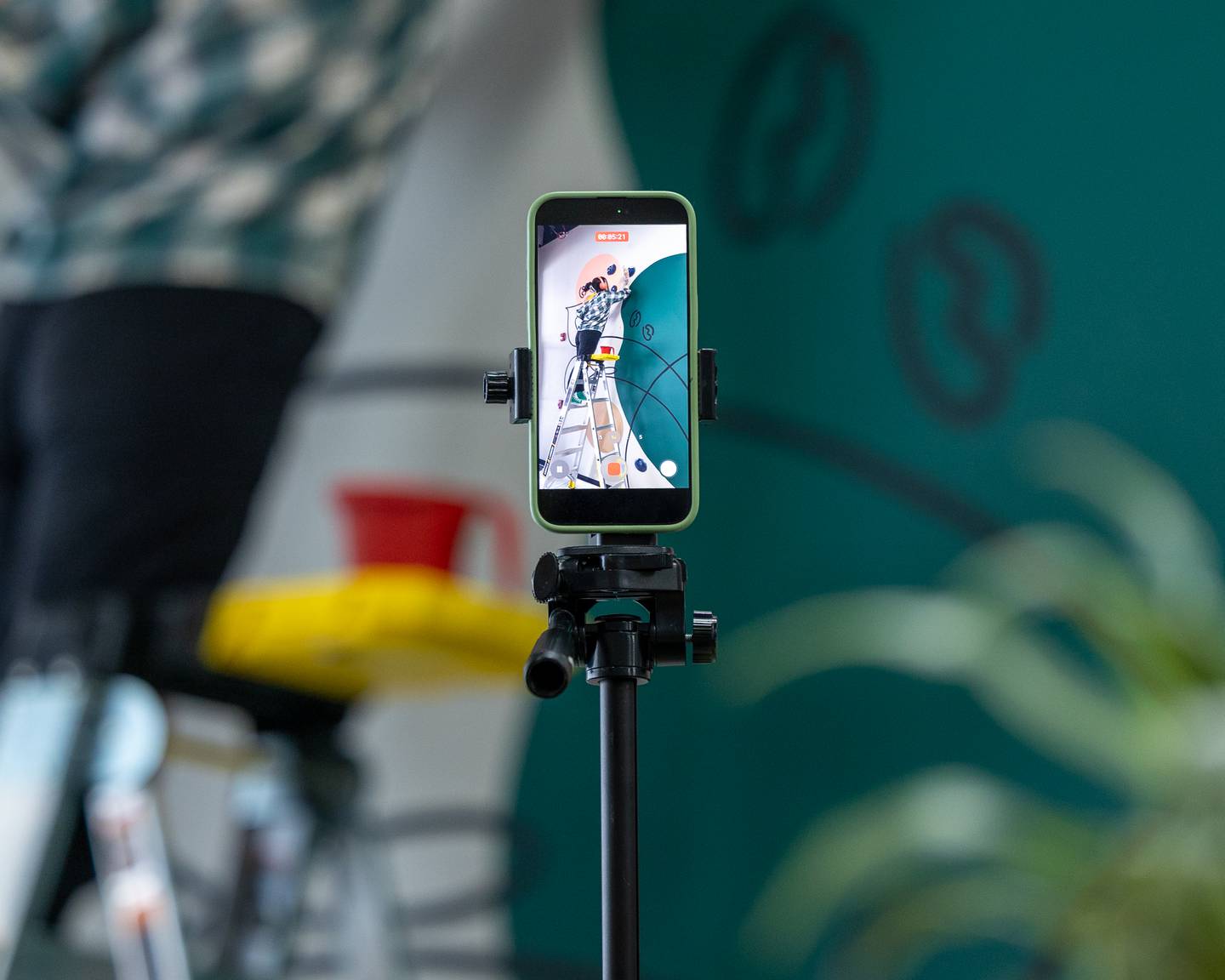 iPhone on tripod records as Lacey Haltenhof of 'The Laced Brush' paints a mural at More Cafe in Ottawa on Monday, Feb. 2, 2026. Lacey recorded the entire painting process to post on her social media accounts promoting her art. You can find her on Social Media @thelacedbrush on Instagram and Facebook.