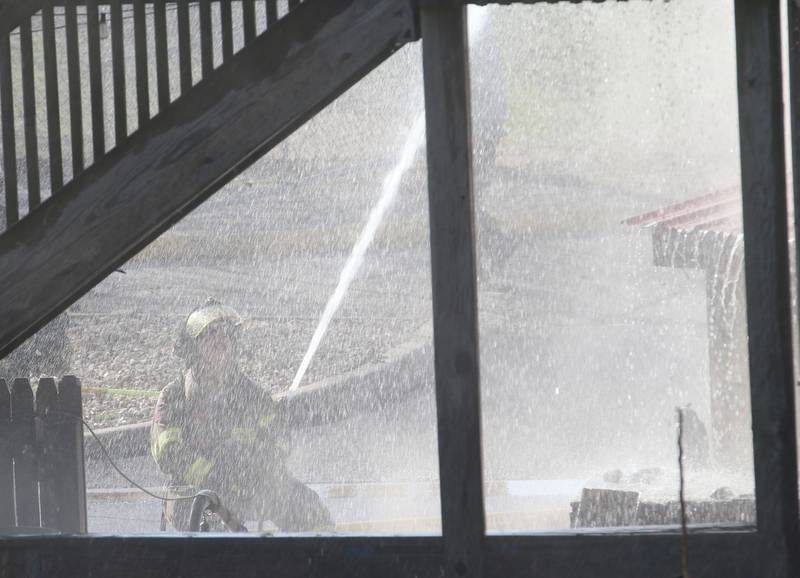 A firefighter uses a hose to spary down the side of a structure fire at the former Platform 31 tavern on Monday, March 24, 2025 on Water Street in Peru. The fire was upgraded to a three-alarm summing ire departments from La Salle, Utica, Mendota, Tonica, Ottawa, Ladd, Spring Valley, Lostant, Cedar Point, Troy Grove and Peru responded to the fire.