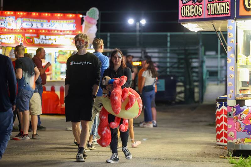 Zoe Dorey, right, of New Lenox, carries several carnival prizes alongside Jackson Choen, of Monee, as they both sported face painting during the Will County Fair on Aug. 21, 2025.