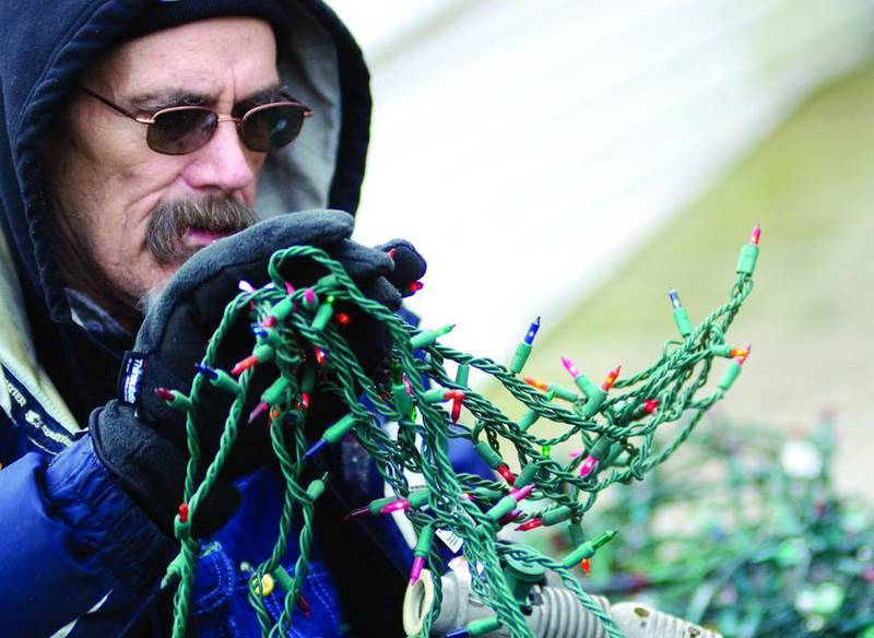 Burt Fuller untangles and tests strings of lights Sunday at his Rock Falls home. Fuller has no idea how many lights he has, but he knows it’s a lot, thanks to an outpouring of  support from the community. Fuller also credits his son, Danny Fuller, and nephew, Eric Wear, for their help decorating. Without them, he said, it’d never get done.
