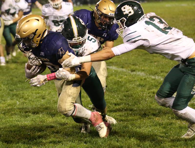 Marquette's Jacob Smith carries the ball as he is brought down from behind by St. Bede's Halden Hueneburg and Evan Entrican. on Friday, Oct. 13, 2023 at Gould Stadium.