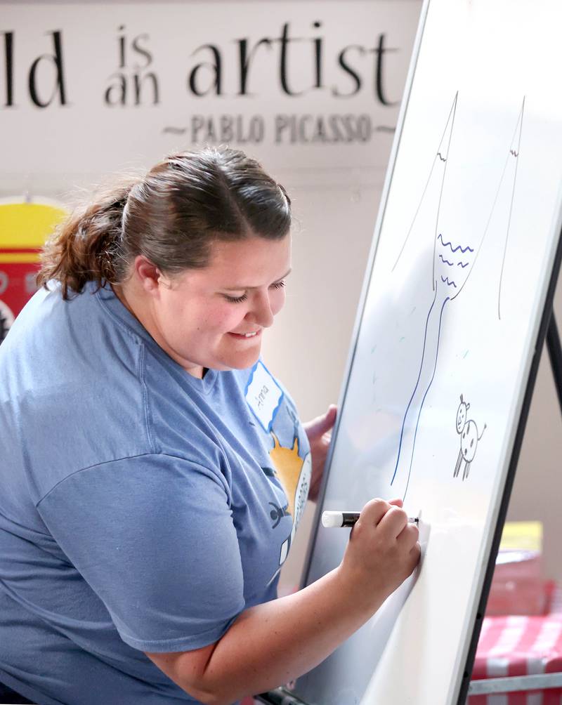 Ana Scott, director of Neighbors' House, draws parts of a Bible verse that is being read Monday, July 11, 2022, during of a session of Summer Reading Vacation put on by Neighbors' House in DeKalb in conjunction with the DeKalb County Farm Bureau. Christ Community Church is hosting the camp this week in their outreach center on North 6th Street in DeKalb.