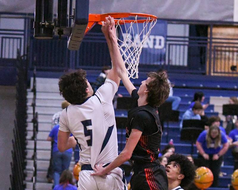 Oswego East's Josh Lopez, left, makes a basket while being defended by Yorkville's DJ Ingemunson (5) during the game on Friday Feb. 14,2025, held at Oswego East High School.