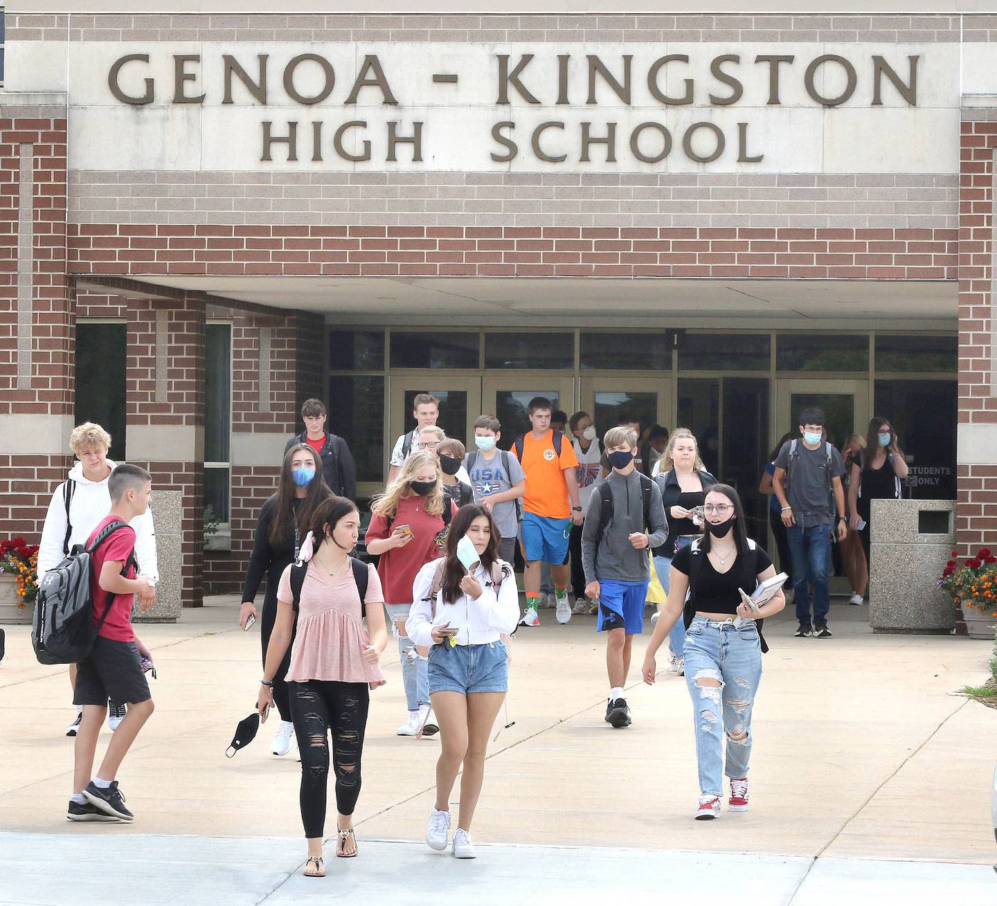 Students remove their masks as they exit Genoa-Kingston High School Monday after finishing up their first day of in-person classes. School District 424 is using a hybrid schedule with a full remote option to start the year.
