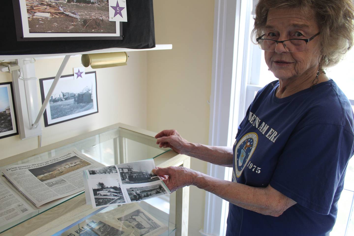 Pat Paul of the Crystal Lake Central High School 1965 class shows pictures of her damaged home after the Palm Sunday tornado ripped through the city.