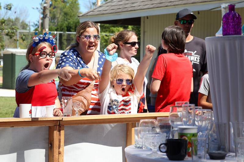 Elaina Pena, 8, right, celebrates throwing a dime into a glass as her sister, Sophia, 9, left, and mother Crystal, all of Manteno, play the Herscher FFA dime toss during the 104th annual Herscher Labor Day Celebration on Monday, Sept. 1, 2025.