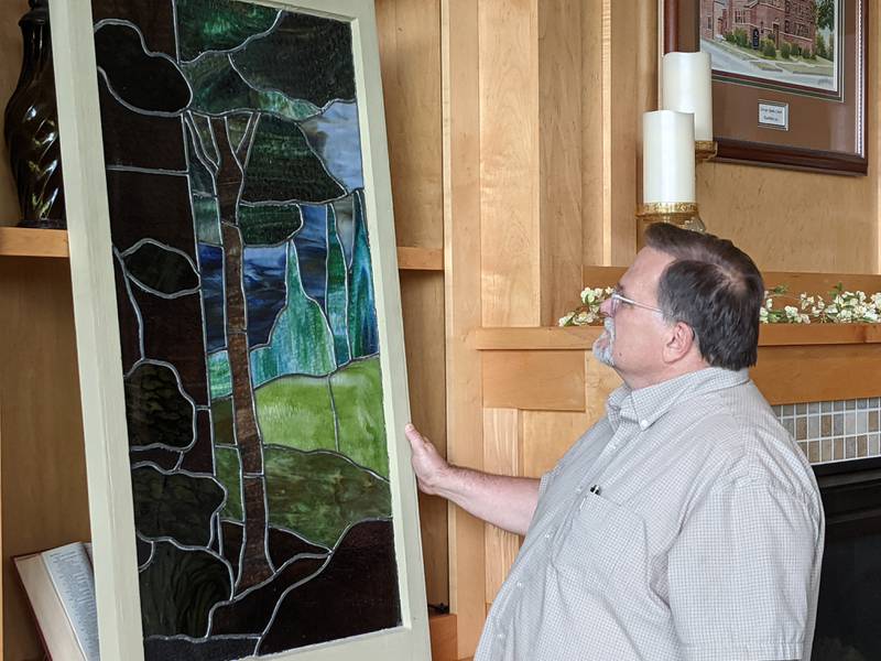 Harvest New Beginnings Executive Pastor Bill Maroney looks at a stained glass window from the church's original building. The church is celebrating its 60th anniversary.