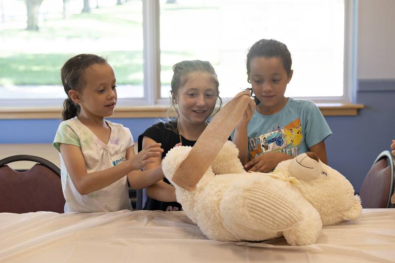 Kendra (left), Raegan and Bridget work together to wrap up a Teddy bear with tape Monday, July 28, 2025, during a workshop on the life of a veterinarian hosted by the University of Illinois Extension and the Whiteside 4-H club at the Rock Falls Library.