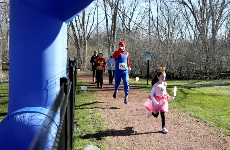 Patrick Quinn of Wheaton, dressed as Mario, follows behind his daughter, Sienna, as Princess Peach, at the finish of the Wheaton Park District’s Superhero 3K Fun Run at the Sensory Garden Playground in Lisle on Saturday, April 6, 2024.