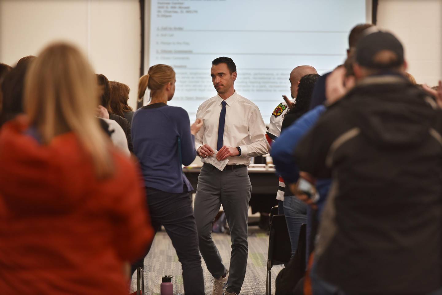 St. Charles North High School teachers Alice Froemling, middle left, and Brian Callahan, facing camera, stand with the audience during the District 303 school board meeting in St. Charles on Monday, April 17, 2023. Both teachers are being involuntarily reassigned to other schools along with several other teachers and a capacity crowd showed their support for the teachers at the meeting.