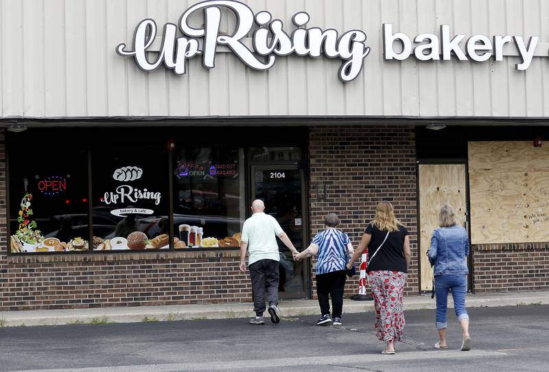 People walk into Uprising Bakery & Cafe in Lake in the Hills, Monday, July 26, 2022, after the store reopened Sunday after its front windows were smashed and epithets written on the walls, to long lines and enthusiastic community support. The cafe, which was planning to host an all-ages drag show Saturday night, had experienced backlash over the previous few weeks.