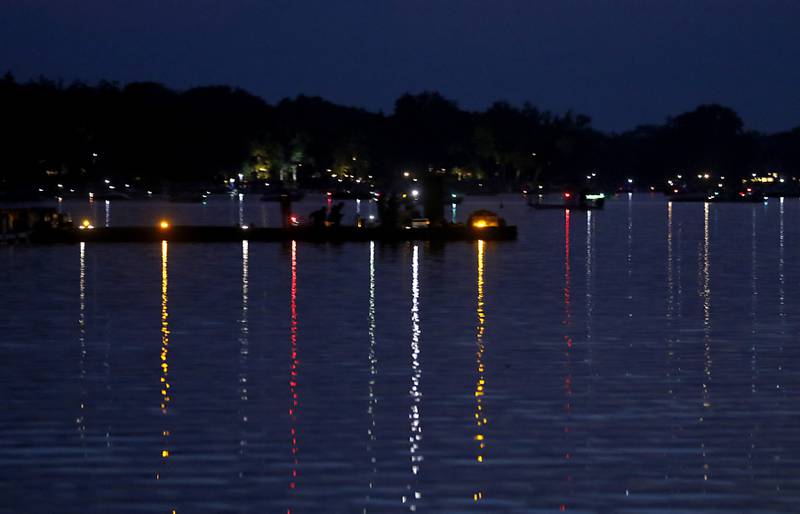 Boat lights are reflected in the waters of Crystal Lake before the fireworks show Sunday, July 2, 2023, at Crystal Lake’s Main Beach during Crystal Lake Annual Independence Day Celebration.