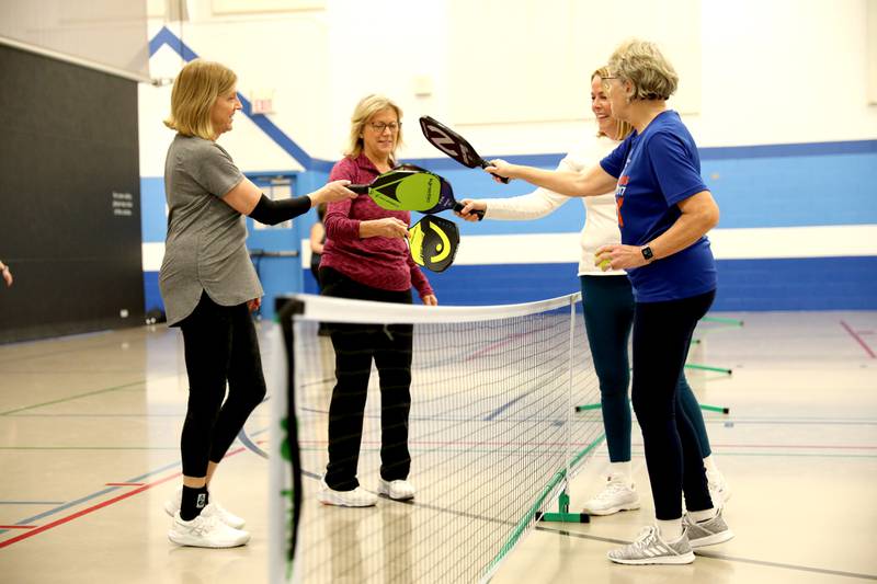 (Right to left) Chris Licht, Laurie Clark, Eileen Parsons and Janet Ballweg gather at the net following a match during a pickle ball open gym session at the Pottawatomie Community Center in St. Charles on Jan. 23, 2023.