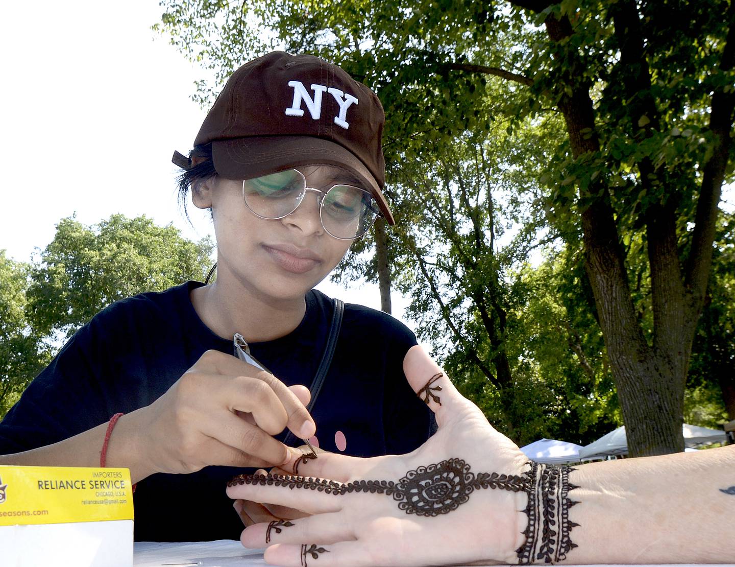 Bhawana applies a henna tattoo for a customer Saturday at Washington Park in Ottawa during the 4th annual Children’s Business Fair.