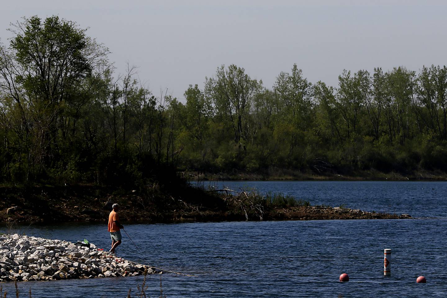 A man fishes along the shoreline Thursday, May 11, 2023, at Three Oaks Recreation Area in Crystal Lake.