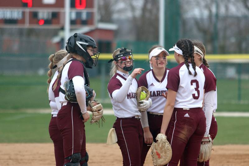 Marengo players share a light moment between innings of a 12-0 win over Harvard in varsity softball at Marengo Thursday.