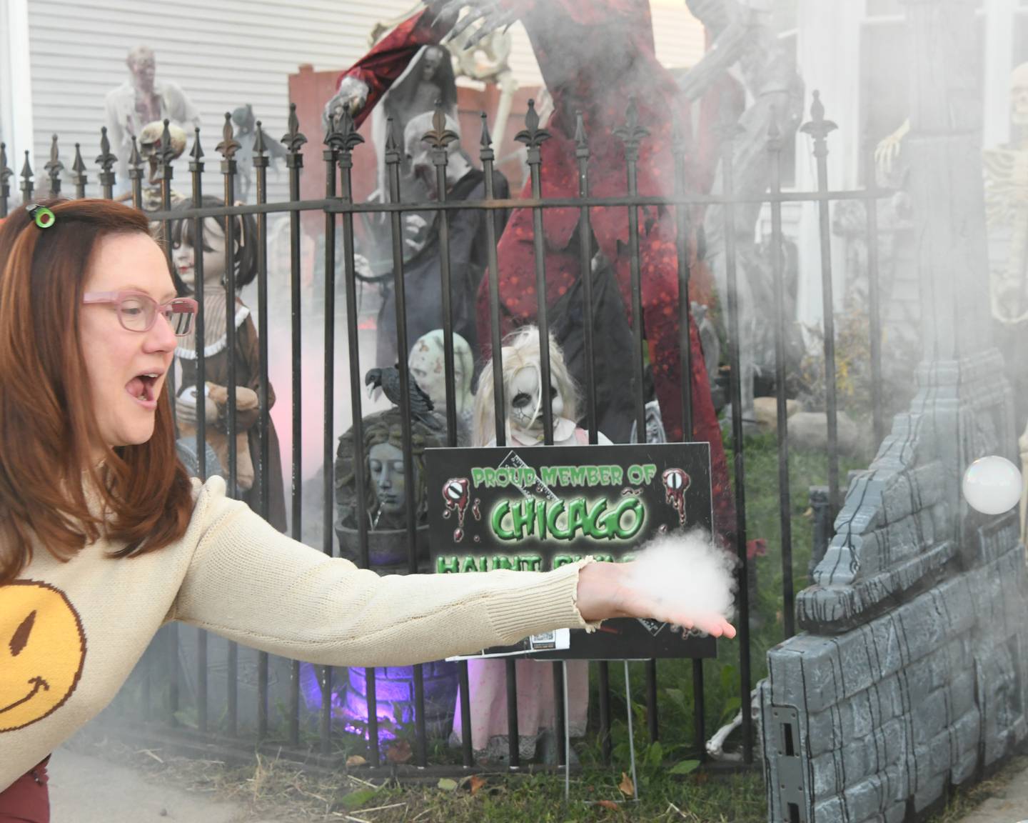 Dannielle Dienoff pops a fog mixed bubbled known as a Fobble that was floating around the front yard during the haunted yard trail on Wednesday on Oct. 16, 2024, held in Oswego.