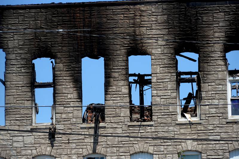 The third floor of a charred apartment building at 406 E. Third St. is silhouetted against the sky on Monday as the investigation into Friday's deadly blaze continued. The building, including two buildings on each side, have been cordoned off with a metal fence, and police tape remains in a two-block area southwest of the scene, including a portion of the municipal parking lot across Fourth Avenue.