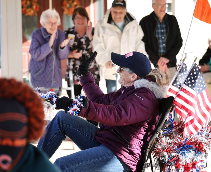 Joann Kunkel, from Sycamore, waves as she rides by residents of the Grand Victorian assisted living facility on Veterans Day,  Friday, Nov. 11, 2022, in Sycamore. Kunkel read a story in the current Midweek that contained a quote from one of the veterans at the facility that lamented the lack of a Veterans Day parade. So she and her grandkids decided to have one for them.