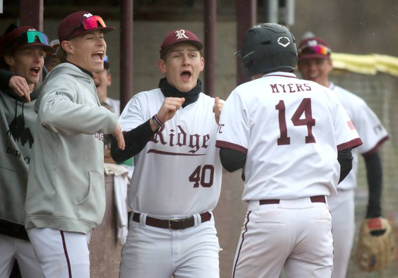 Prairie Ridge’s Gavin Piekos, center, and others greet Ryan Myers after Myers scored against Jacobs in varsity baseball on Wednesday, April 9, 2025, at Prairie Ridge High School in Crystal Lake.