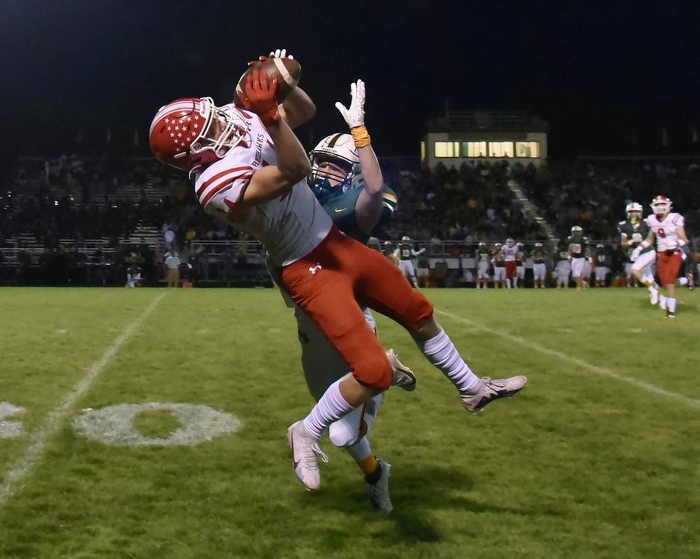 Naperville Central's Logan Devick catches a long pass as Waubonsie Valley's Nico Skuja defends Friday in Aurora.